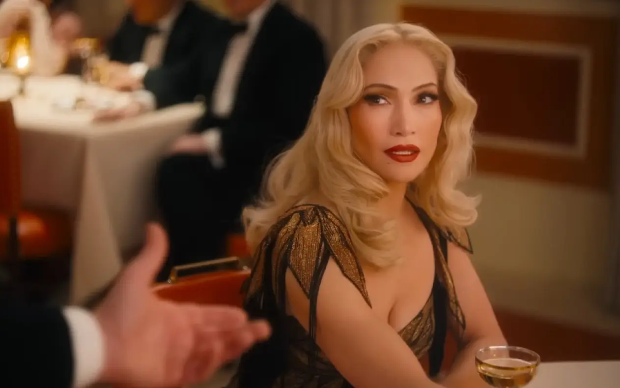 Jennifer Lopez sa dugom talasastom plavom kosom i čipkastoj haljini dok ima ozbiljan izraz lica