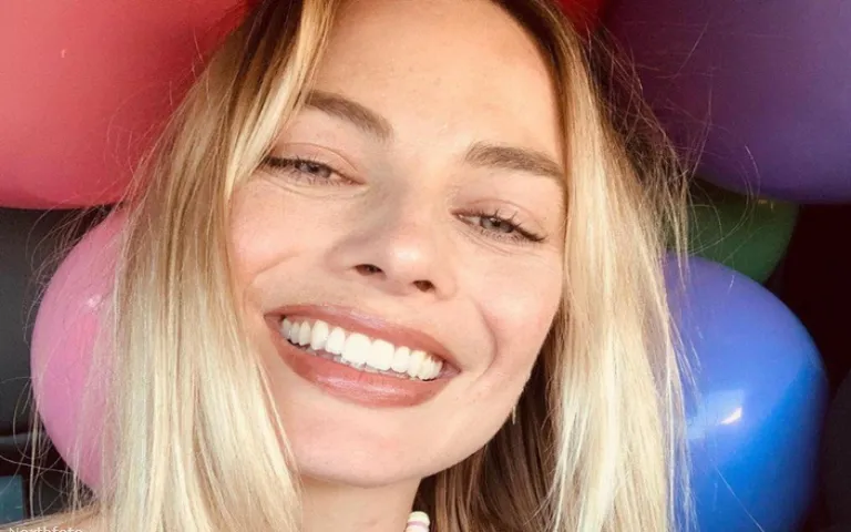 Margot Robbie sa širokim osmehom pozira ispred šarenih balona