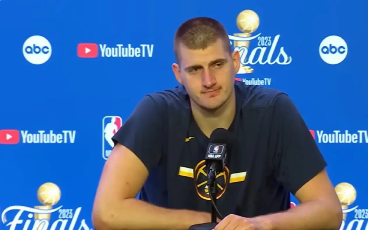 Nikola Jokić govori na konferenciji za medije tokom NBA finala 2023, nosi kratku košulju sa šarom, gestikulira rukama,