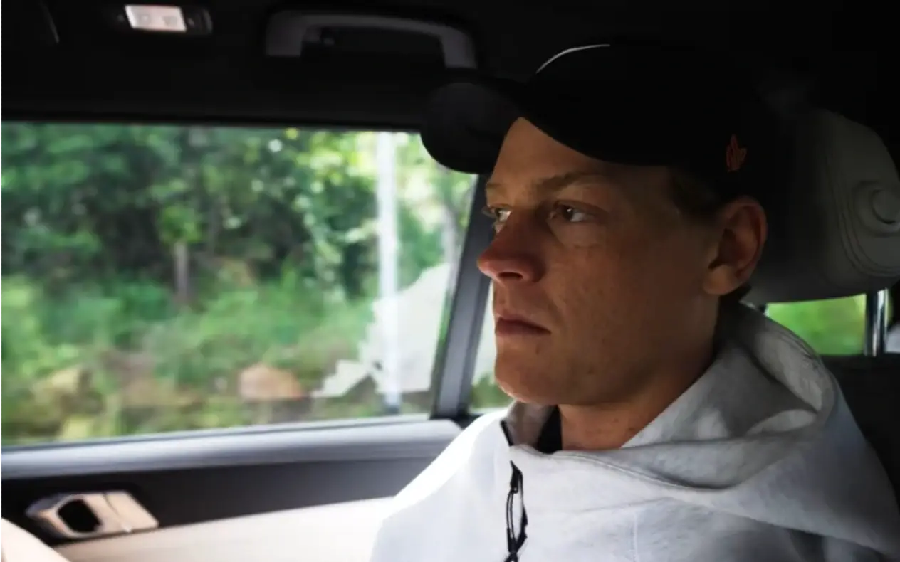 Jannik Sinner tokom vožnje kolima u dukserici i sa kačketom na glavi