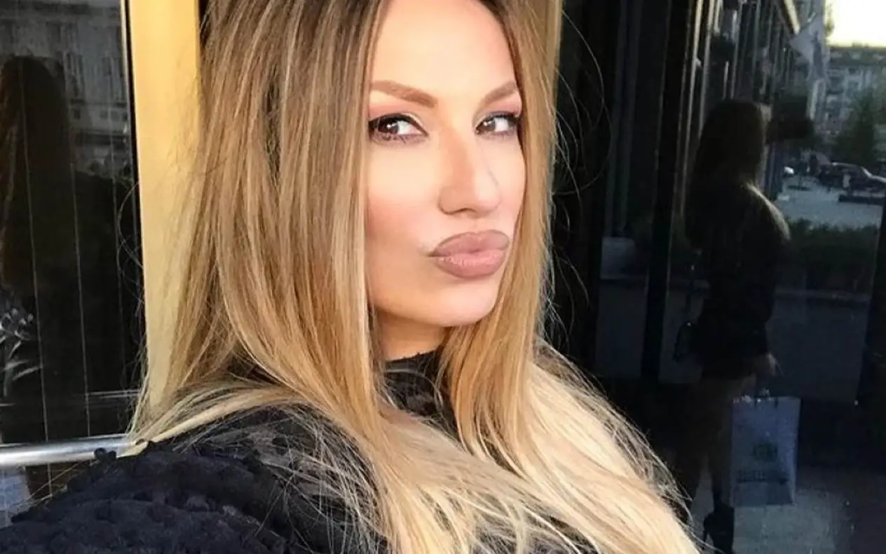 Rada Manojović sa širokim osmehom na lici dok levom rukom drži kosu
