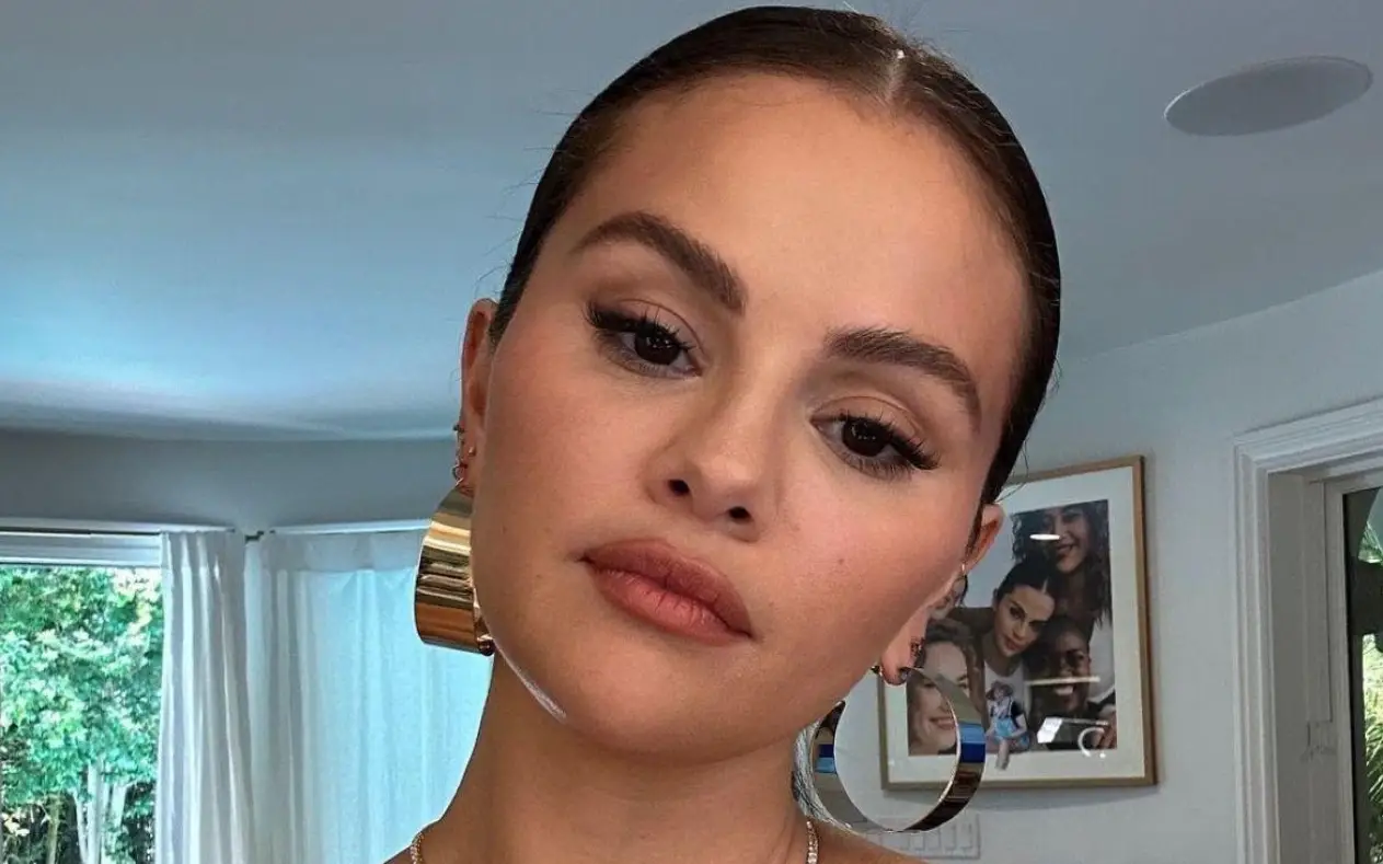 Selena Gomez pozira u zatvorenom prostoru sa zalizanom kosom, zlatnim minđušama i prirodnim makeupom.