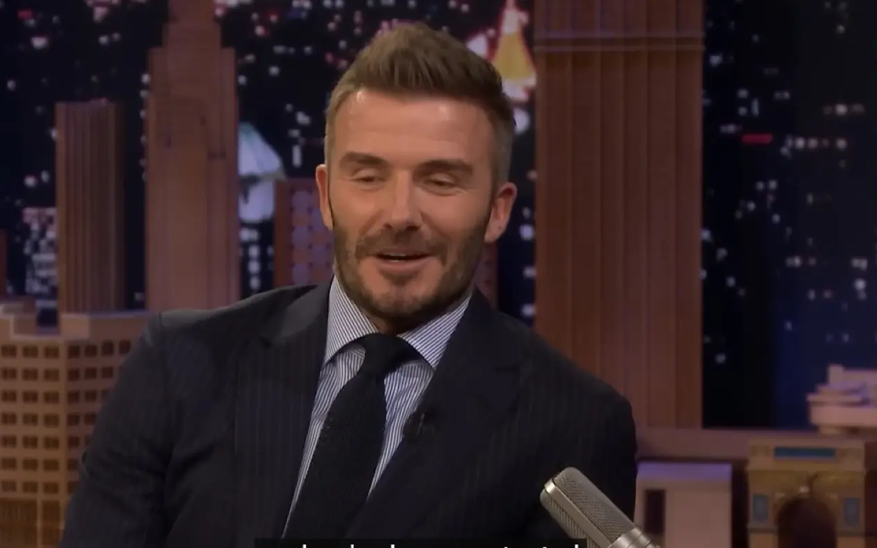 David Beckham  u braon sakou i beloj majici sa ozbiljnim izrazom lica tokom gostovanja u emisiji