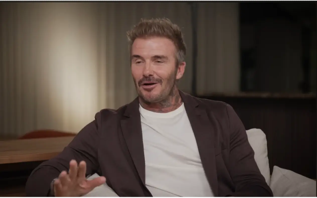 David Beckham  u braon sakou i beloj majici sa ozbiljnim izrazom lica tokom gostovanja u emisiji
