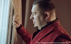 Amar Gile u crnoj košulji i crvenom sakou - gleda kroz prozor