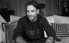 Liam Payne sedi na trosedu gledajući u kameru i obraća se fanovima sa blagim osmehom na licu