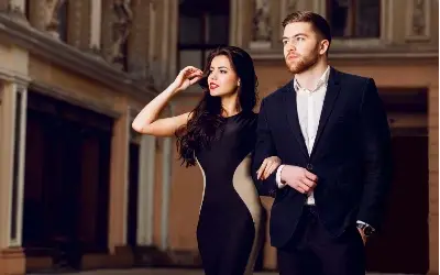 Muškarac i žena se drže ruku pod ruku u elegantnoj odeći