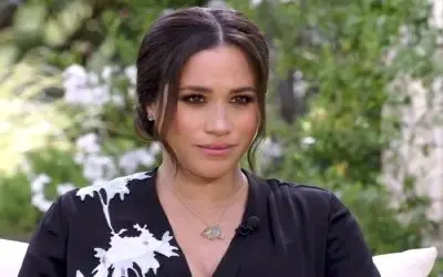 Meghan Markle prikazana izbliza dok daje intervju, obučena u crnu  haljinu sa cvetovima