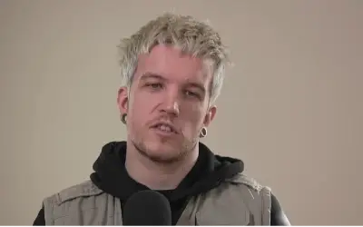 Baby Lasagna emisiji Baby Lasagna u sivom prsluku i crnoj dukserici sa kapuljačom tokom gostovanja u podcastu