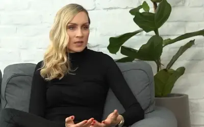 Jelena Gavrilović - intervju Jelena Gavrilović u crnoj rolci - sedi na sivoj garnituri - cveće u pozadini