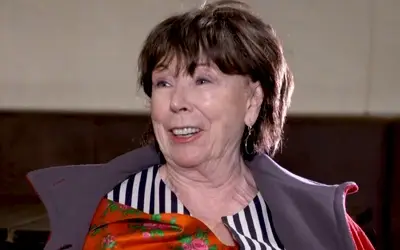 Seka Sablić, sa osmehom na licu gostuje u TV emisiji Seka Sablić u crvenom kaputu i sa šarenom ešarpom