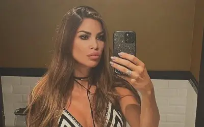 Olja Crnogorac selfi u ogledalu Olja Crnogorac snima selfi u ogledalu, obučena u crno-belu haljinu sa dubokim dekolteom, sa dugom talasastom kosom i elegantnom šminkom.