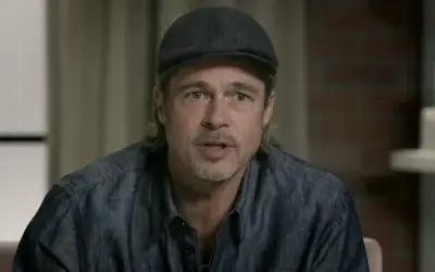 Brad Pitt u sivoj košulji i sa kačketom na glavi