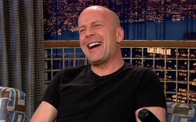 Bruce Willis u crnoj majici sa osmehom na licu