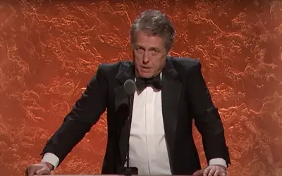 Hugh Grant u crnom sakou i beloj košulji sa leptir mašnom