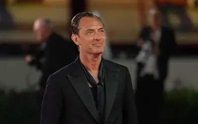 Jude Law tokom na crvenom tepihu Jude Law u crno odelu sa osmehom na licu