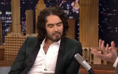Russel Brand u crnom odelu i beloj košulji tokom gostovanja u emisiji