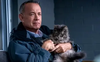 Tom Hanks tokom snimanja filma "Čovek po imenu Oto" Tom Hanks u jakni. sedi držeći majčku u naručju