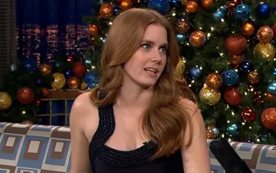 Amy Adams tokom gostovanja u popularnoj tv emisiji. Amy Adams u crnoj haljini u pozadini okićena jelka.