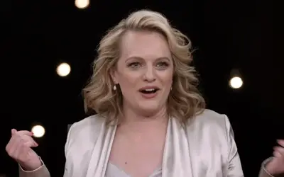 Elisabeth Moss u popularnoj tv emisiji Elisabeth Moss u beloj haljni- sa osmehom na licu