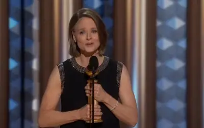 Jodie Foster tokom dodele Oskara Jodie Foster u crnoj haljini istoji ispred mikrofona, sa nagradom u ruci