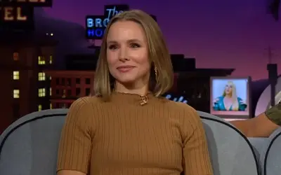 Kristen Bell tokom gostovanja u popularnoj tv emisiji. Kristen Bell u oker bluzi - sa osmehom na licu
