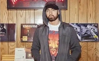 Reper Marshall Mathers Eminem pozira Eminem u dukserici, šarenoj majci i sa kačketom dok pozira sa ozbiljnim izrazom lica