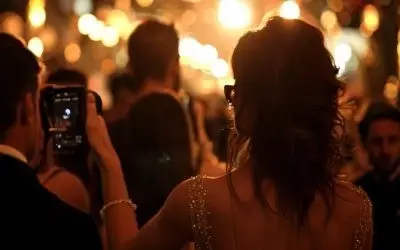 Žena fotografiše događaj na svečanoj večeri sa zlatnim osvetljenjem