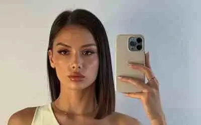 Anja Blagojević u beloj haljini drži telefon i slika selfi ispred ogledala
