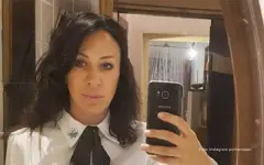 Romana Panić u beloj košulji sa crnom kravatom se slika u ogledalu