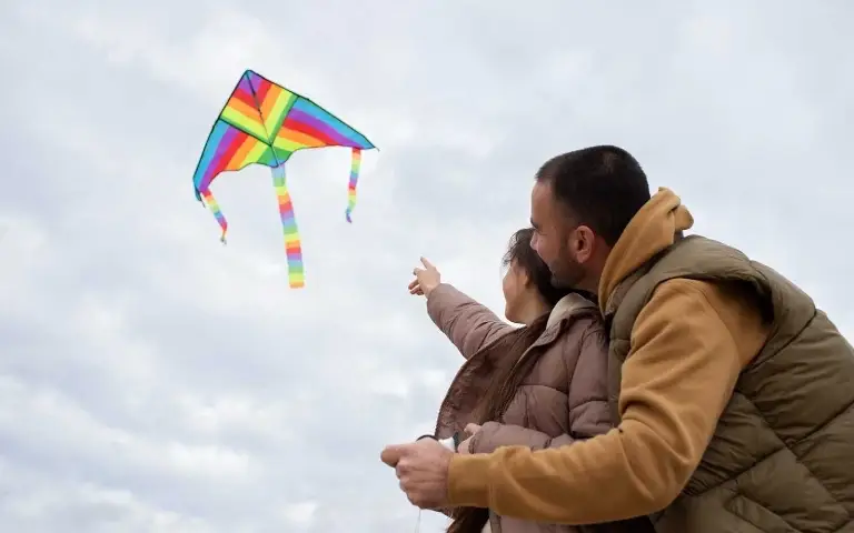 Devojčica sa tatom pušta šarenog zmaja ka nebu