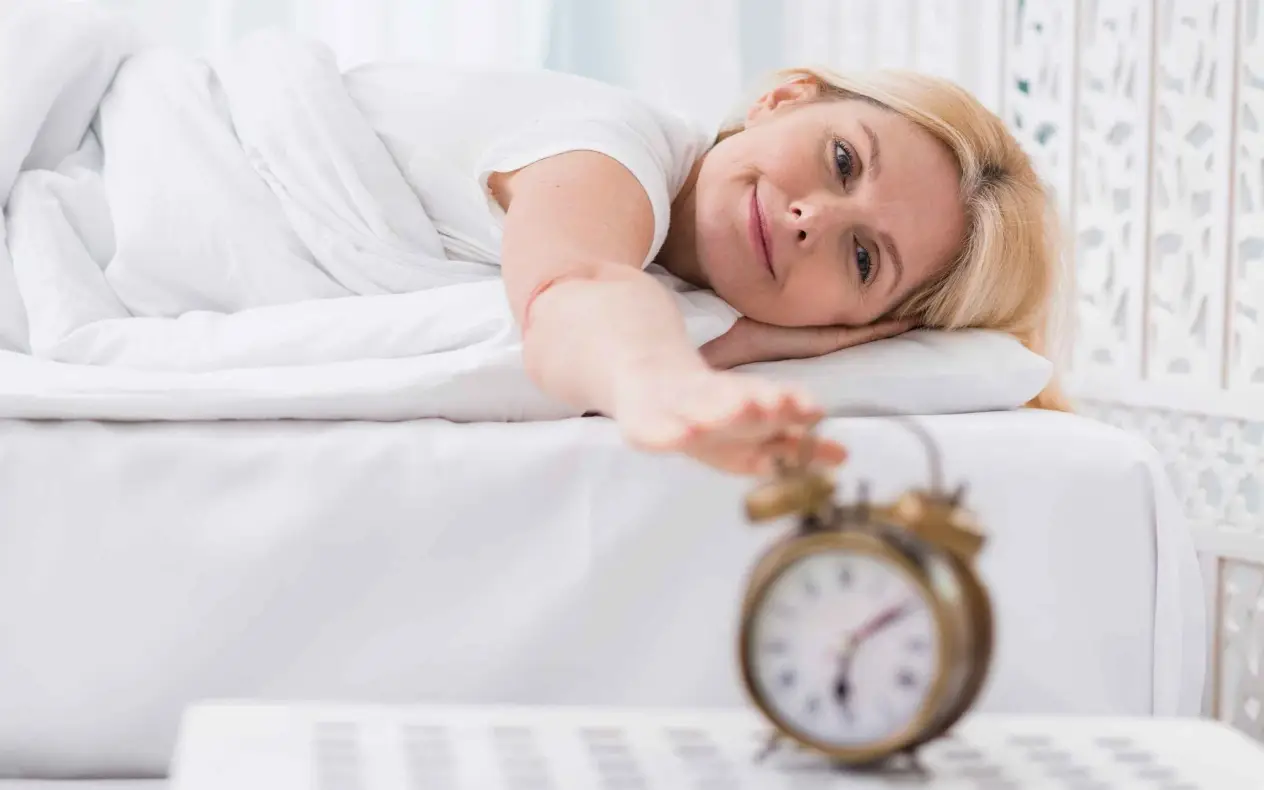 Žena leži u krevetu i gasi alarm