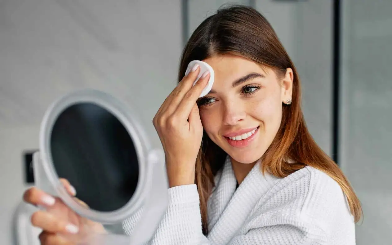 Devojka čisti lice ispred ogledala