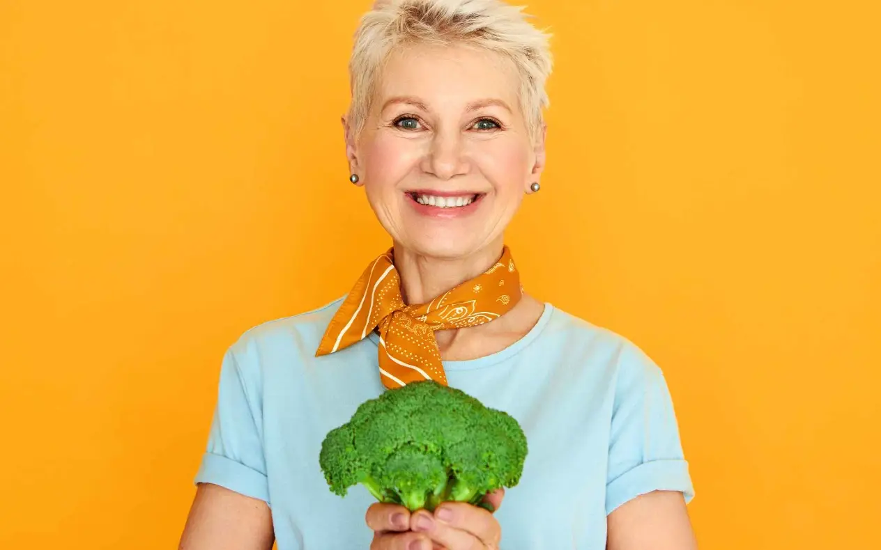Nasmejana žena drži brokoli u ruci