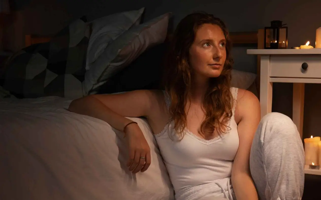 Žena sedi pored kreveta -  zamisljena