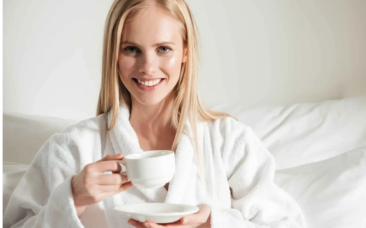 Devojka u krevetu pije prvu jutarnju kafu