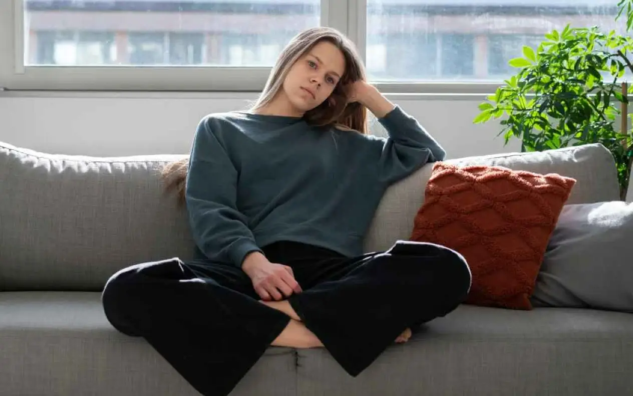 Devojka sedi zamišljena u dnevnoj sobi