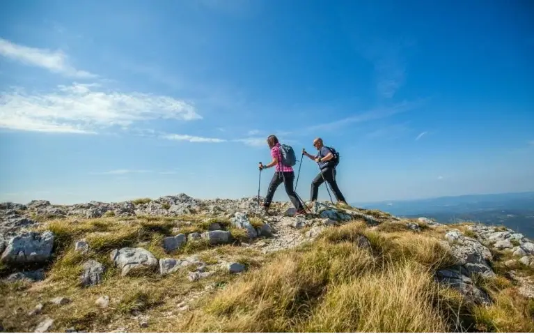 Dvoje ljudi sa štapovima hodaju po planinama delovima u Austriji