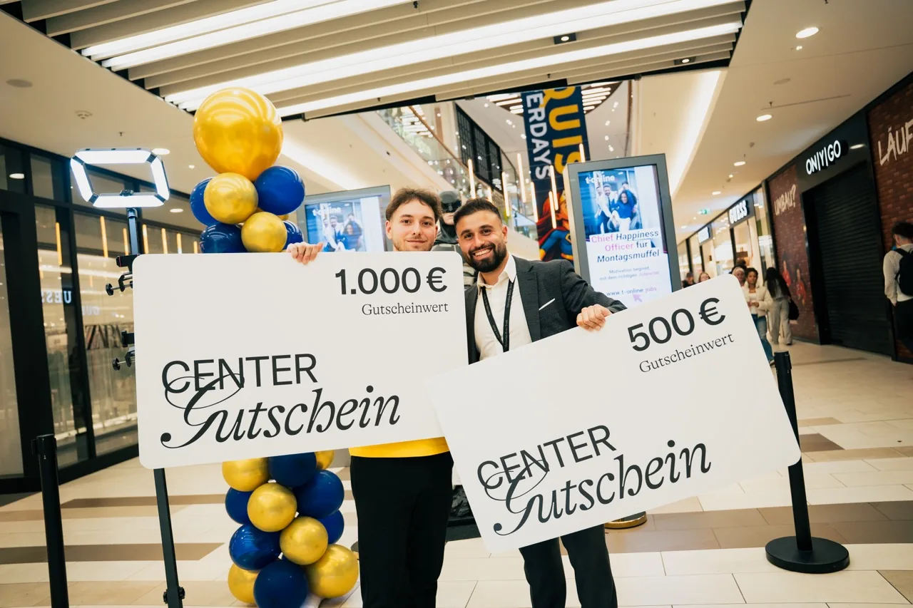 Fynn Frings und Youssef Ismail halten übergroße Center-Gutscheine über 1.000 € und 500 €