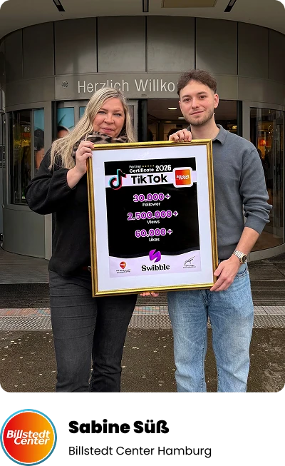 Sabine Suess und Fynn Frings halten vor dem Billstedt Center das gerahmte TikTok-Zertifikat