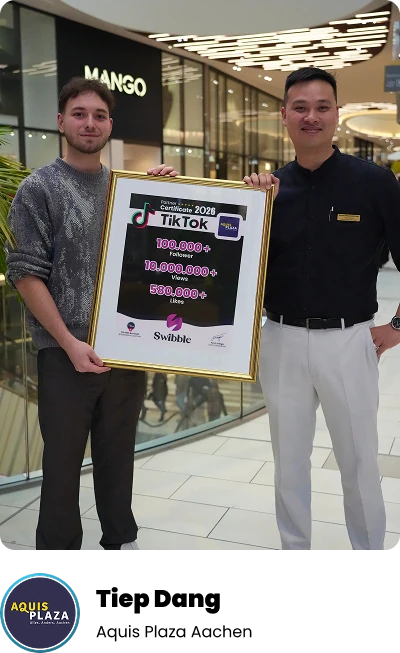 Tiep Dang und Fynn Frings halten im Aquis Plaza das gerahmte TikTok-Zertifikat für mehr als 100.000 Follower