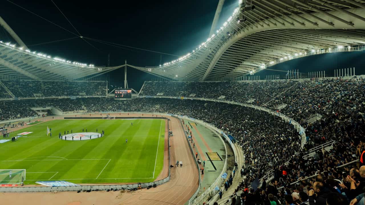 A crowded soccer stadium under bright lights at night, capturing the excitement of a live sports event.