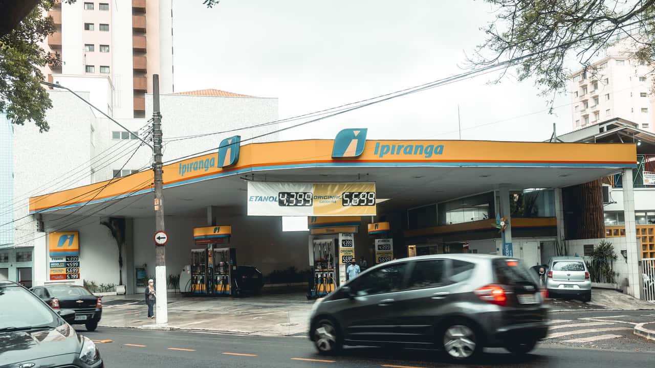 Ipiranga gas station with moving vehicles on a bustling city street.