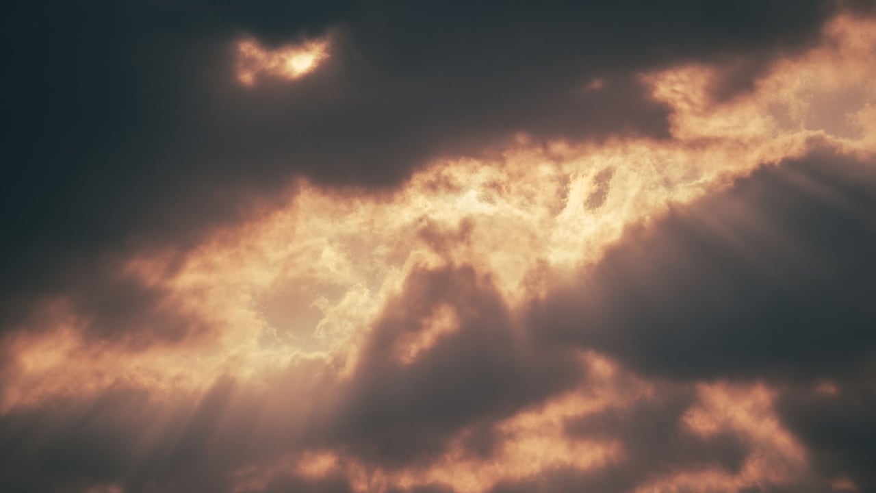 Sunlight piercing through dramatic dark clouds creating a mystical atmosphere.