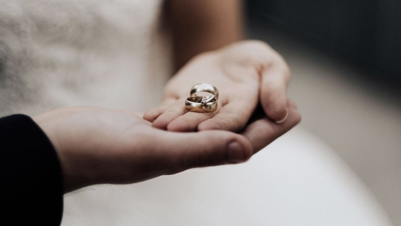 Bride holding wedding bands in a tender moment, symbolizing love and commitment.