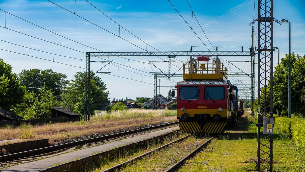 A vibrant train on railway tracks at a rural station in Kutina, Croatia.