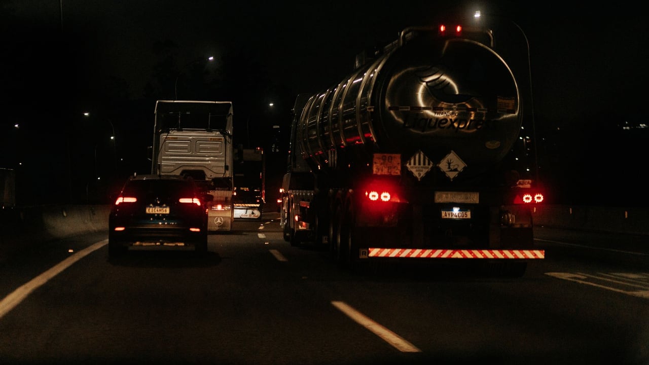 Vehicles drive down a dark highway at night, showcasing traffic and car lights.