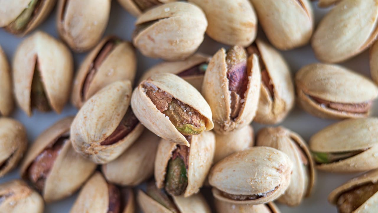 Macro photograph highlighting salted pistachios in their shells, showcasing detail and texture.