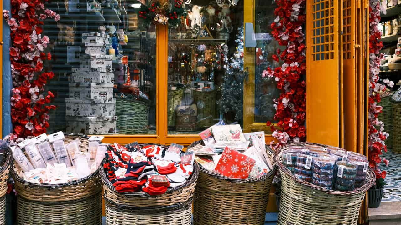 A festive storefront display featuring baskets of wrapped Christmas gifts and vibrant decorations.
