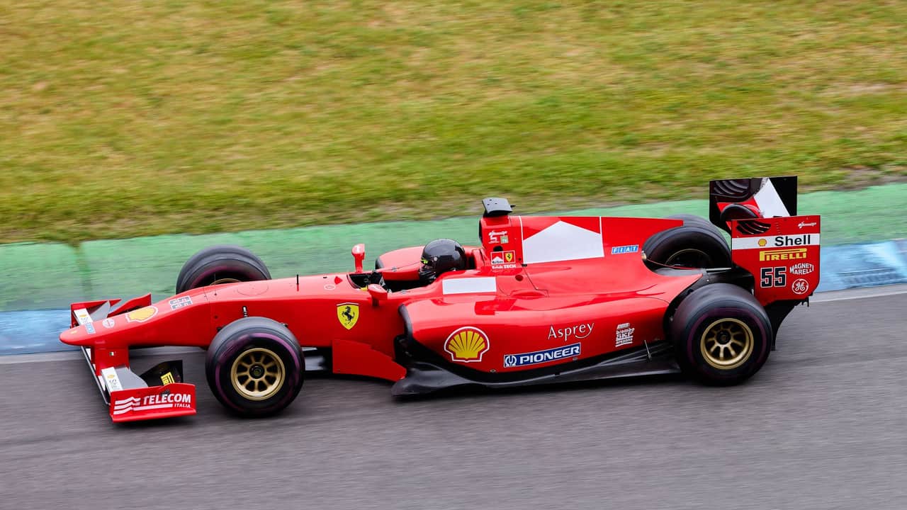 High-speed Formula 1 car in action on an outdoor racing track, showcasing motion and excitement.